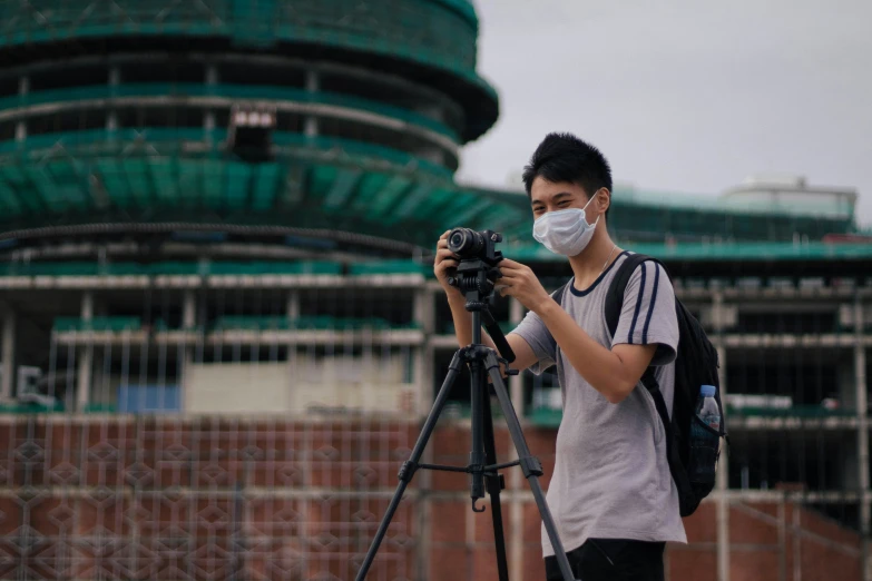 the man with a camera is wearing a face mask
