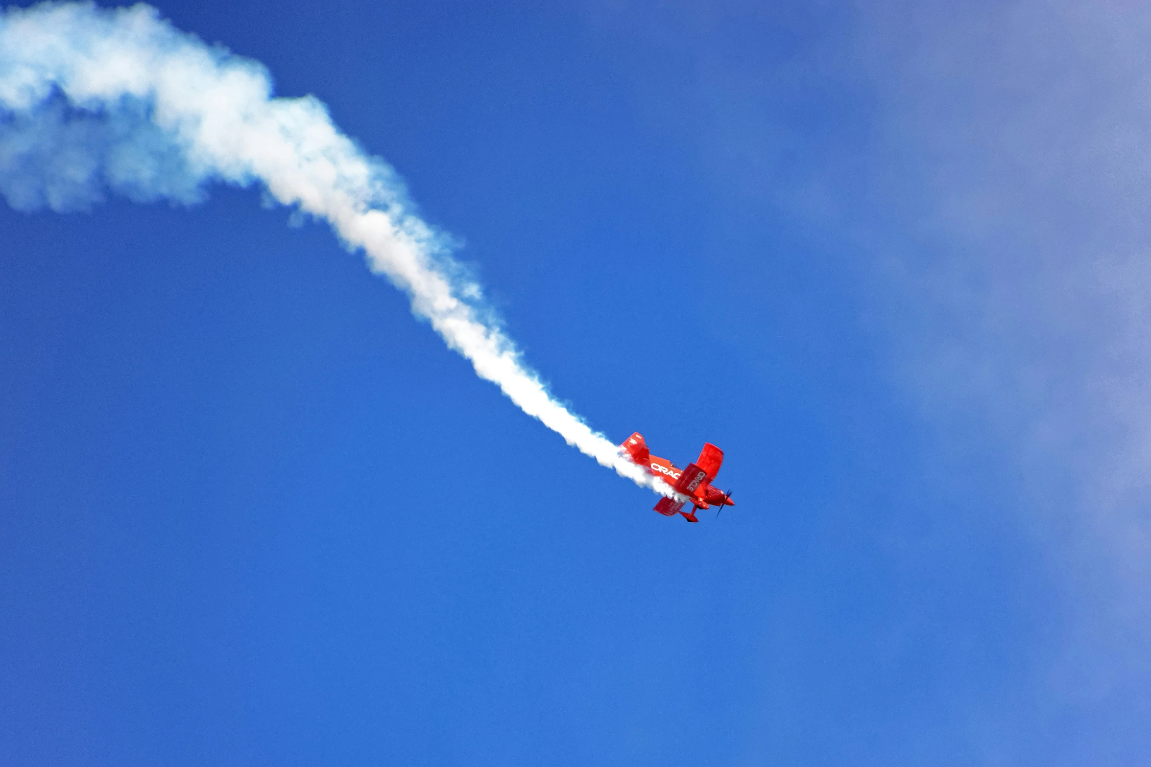 an airplane is trailing smoke against a clear blue sky