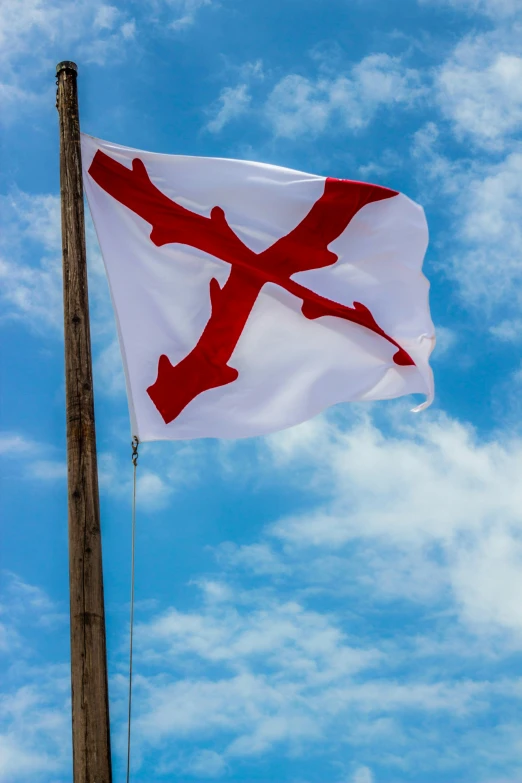 a flag flying in the wind under a blue sky