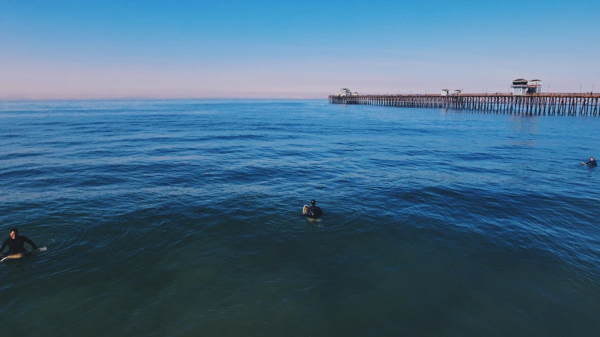 three people are in the water waiting for a wave