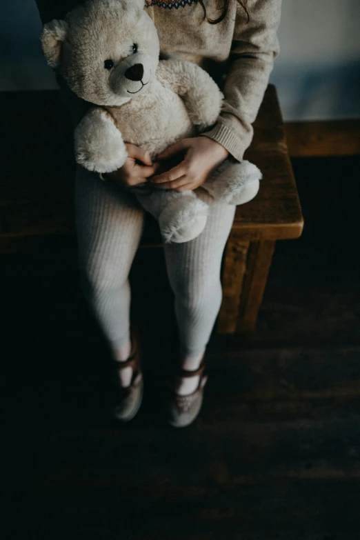 a young woman sitting down holding a white teddy bear