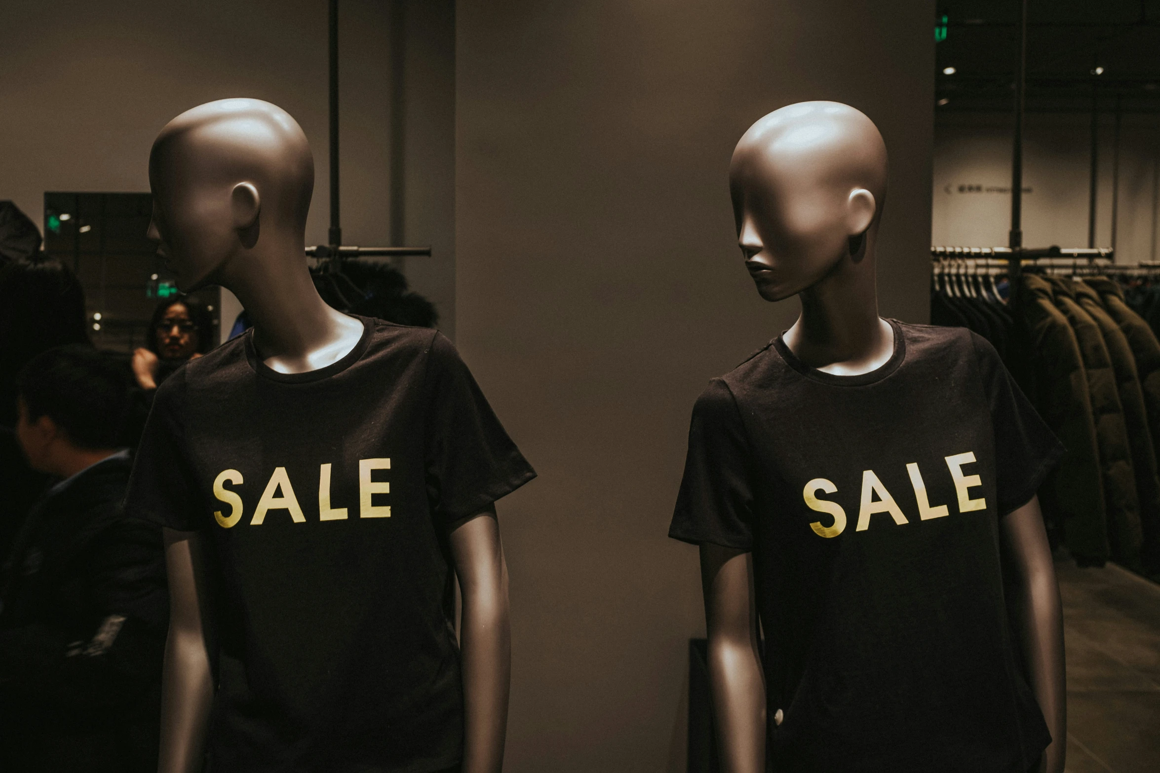 a pair of mannequins are displaying black shirts for sale