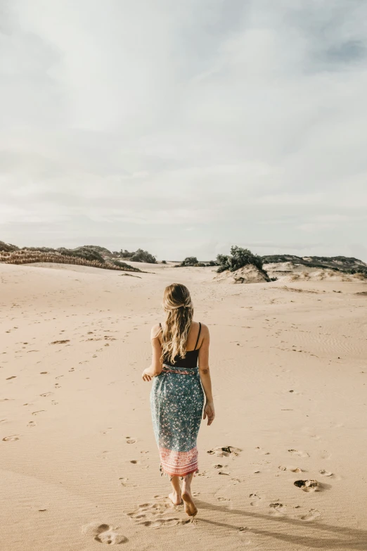 a woman walking across a sandy beach