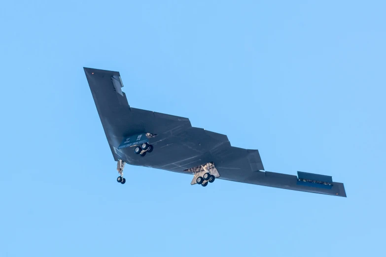 a military aircraft flying through the air, viewed from below