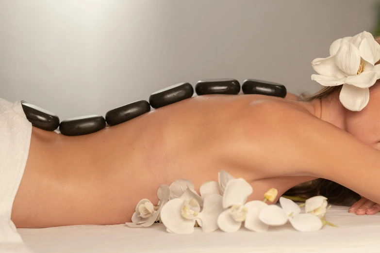 an attractive woman laying down wearing black beads on her head and white flowers in her hair