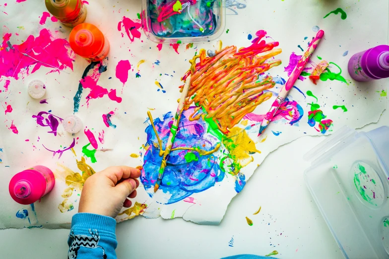 a child using different colored paints on white paper