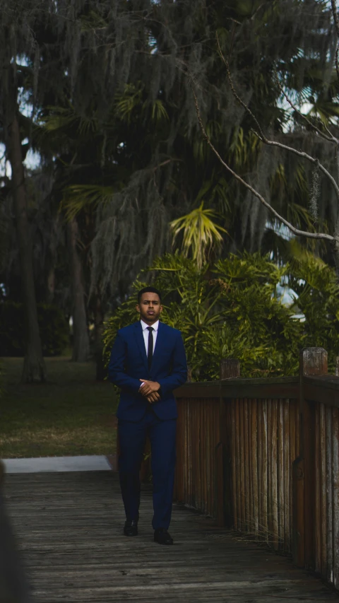 a man is walking on a bridge in a blue suit