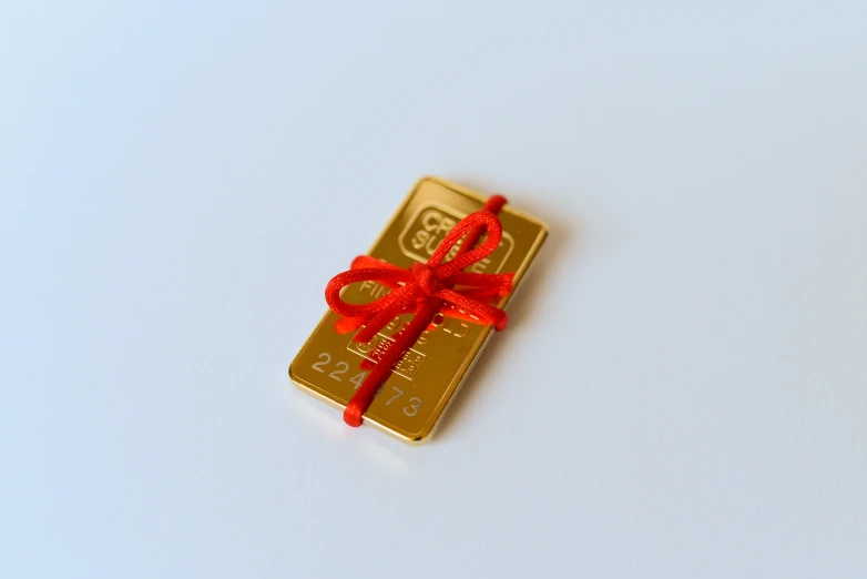 a gold bar with a red ribbon on it