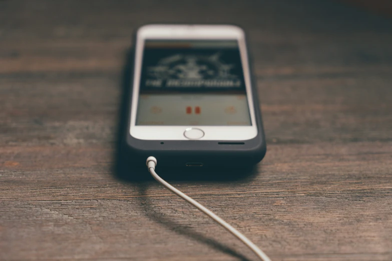 a small cellphone with headphones is resting on a table