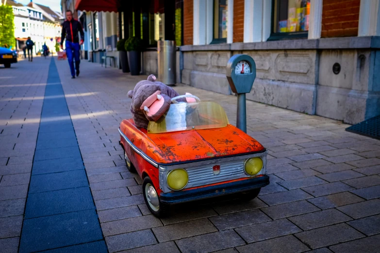 a stuffed animal in an orange car on the street