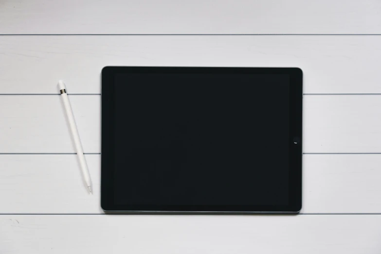 a small black tablet next to a white pencil