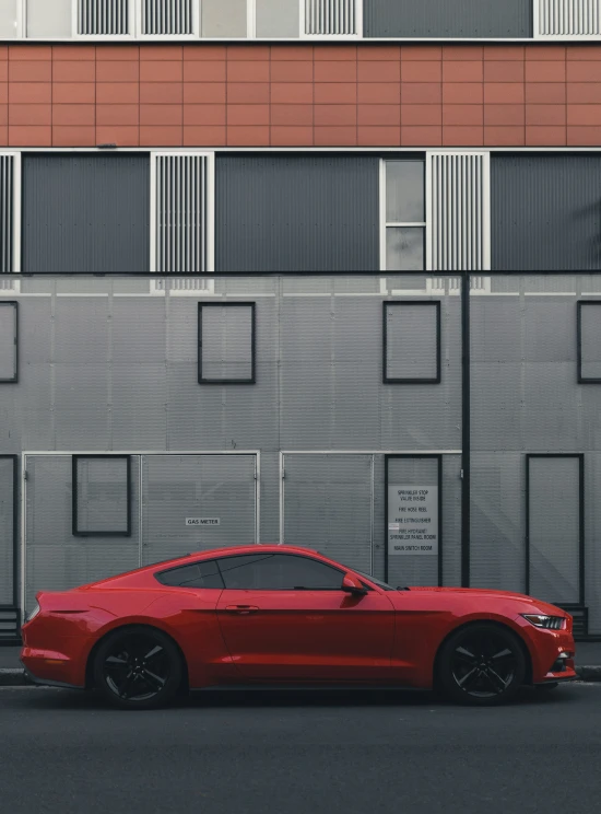 a red mustang car parked on the side of a road