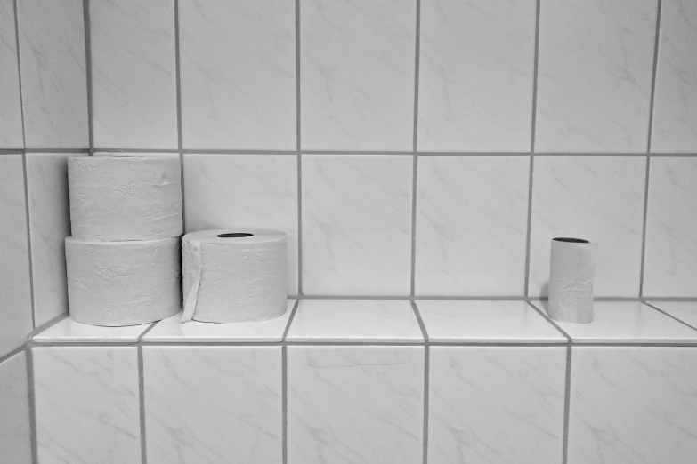 three rolls of paper towels next to some toilet paper