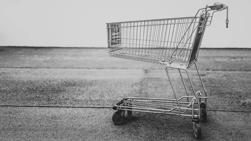 an empty shopping cart sits on the sidewalk