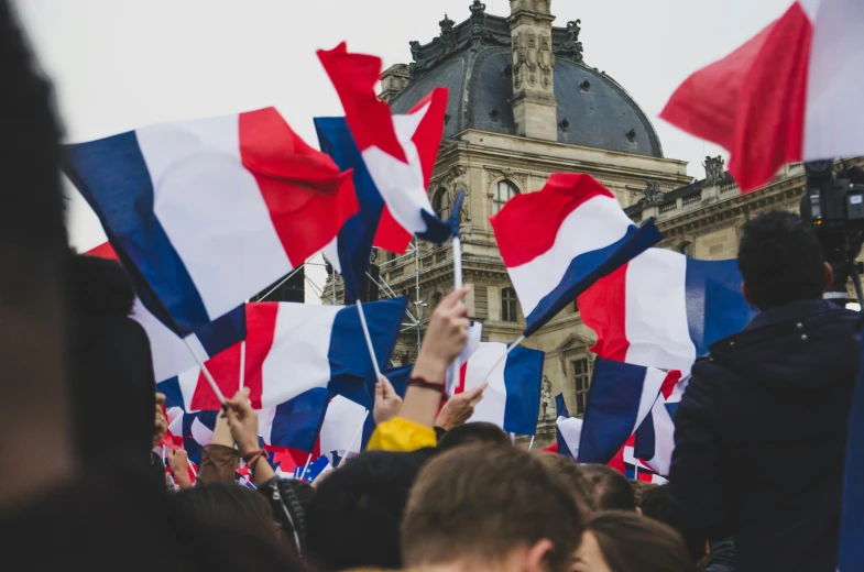 many people are holding small colorful flags in the air