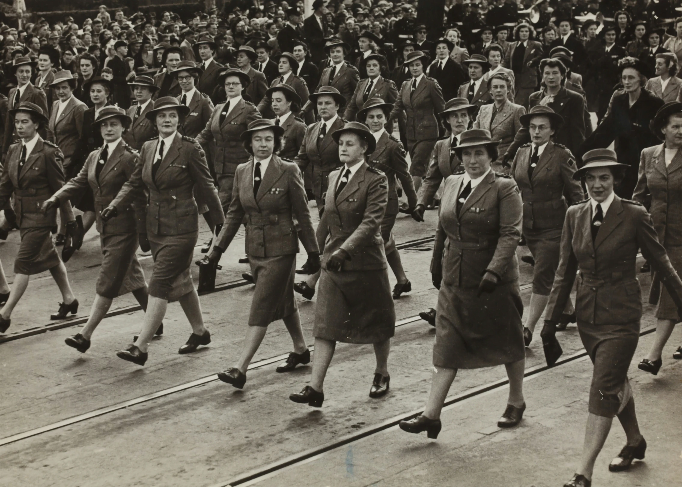 women in old time uniforms walking through a crowd