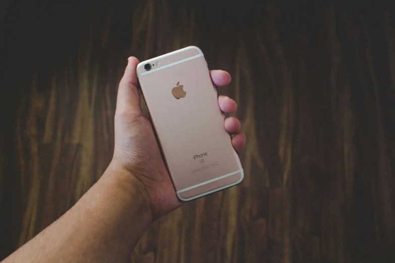 a person is holding up a pink apple phone