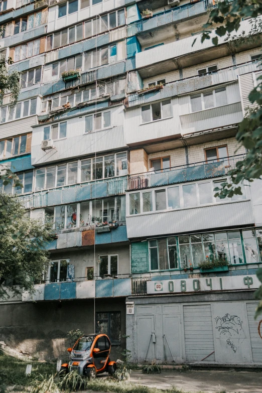 a tall building with balconies that overlooks the trees and grass