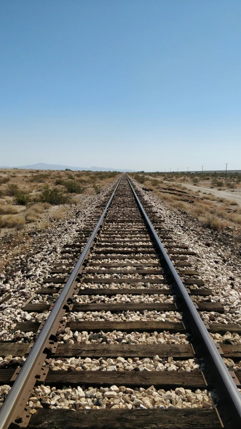 the view from the top of an empty railroad tracks in a field