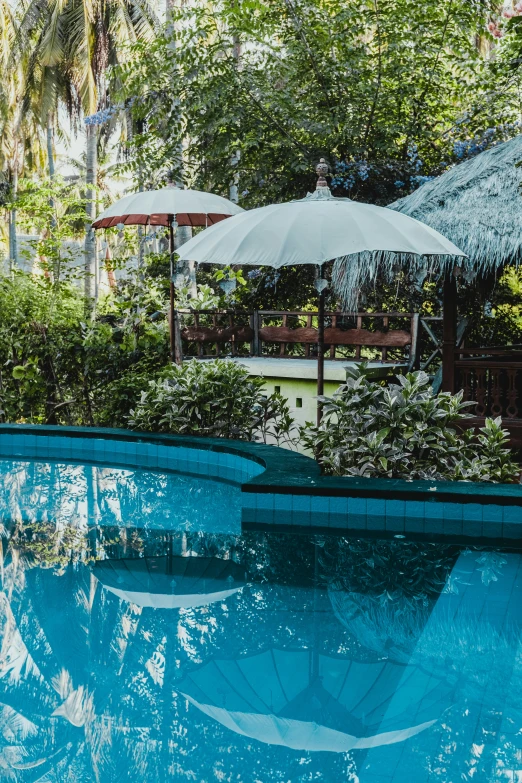 a pool that has a umbrella and chairs near it