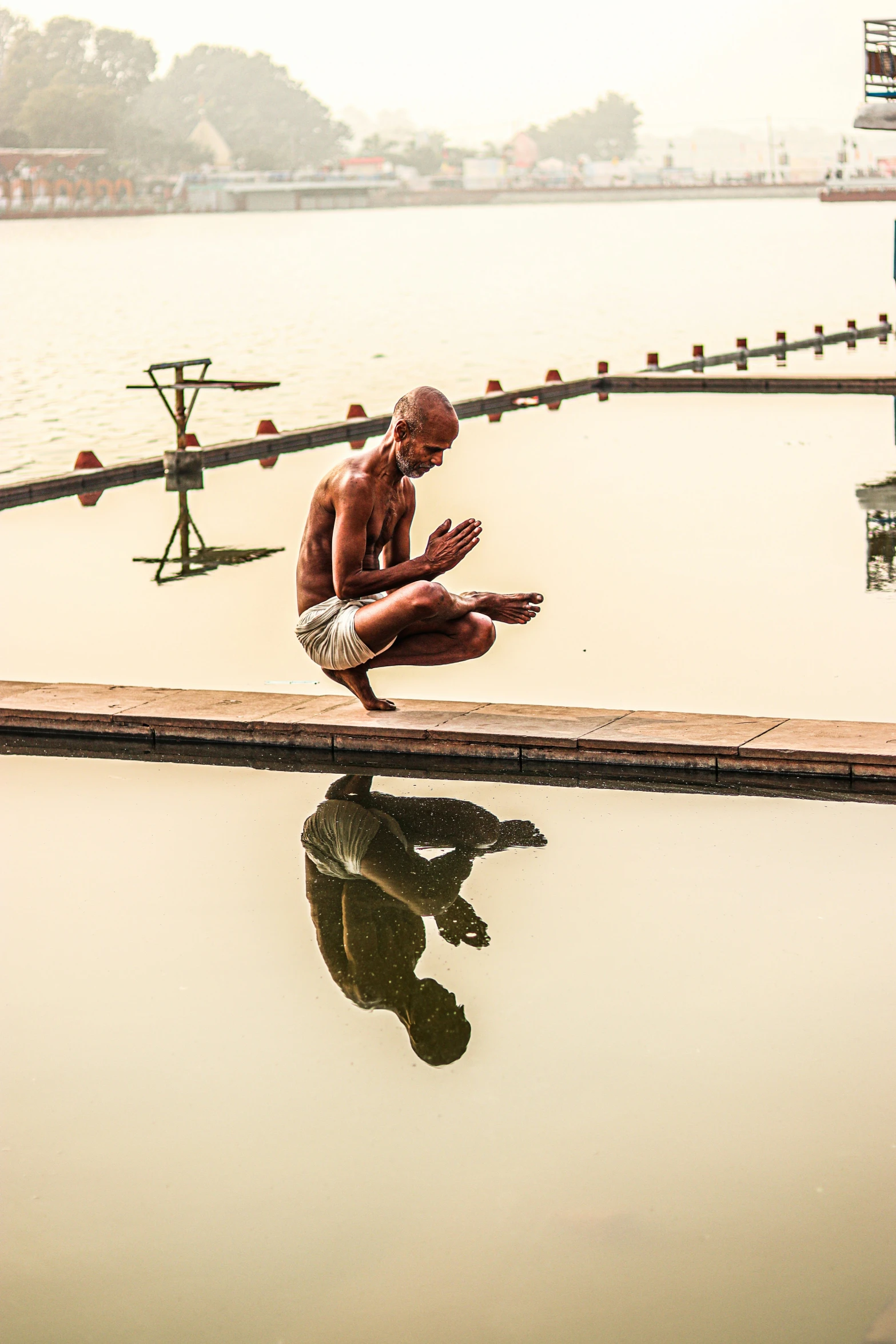 a man sitting on a ledge by the water