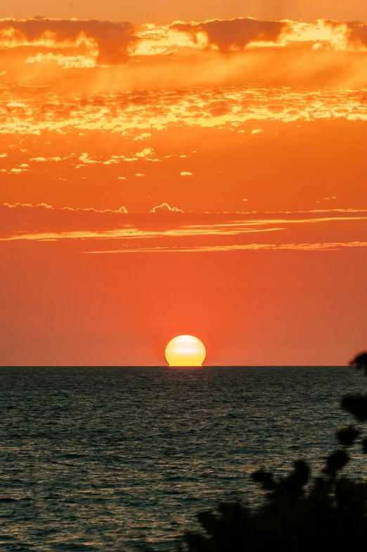 the sun is rising over the water at sunset