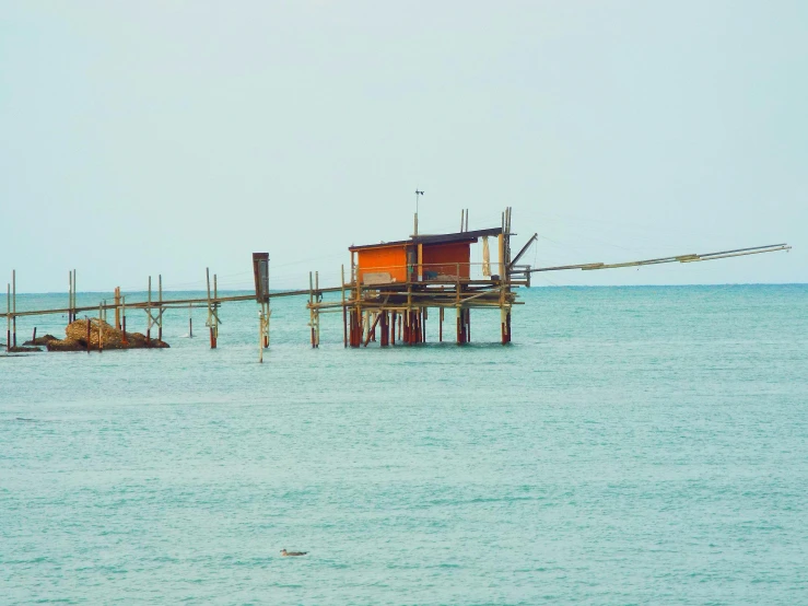 a beach hut sitting on top of a small wooden structure in the middle of water