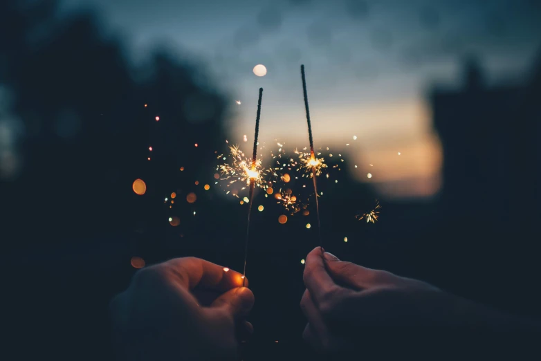 two people holding small sparklers in their hands