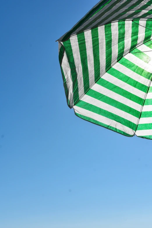 an open green and white umbrella in a clear sky