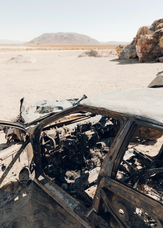 there is an old burned out car that has been parked in the desert