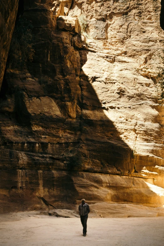 a man standing next to a big wall of rock