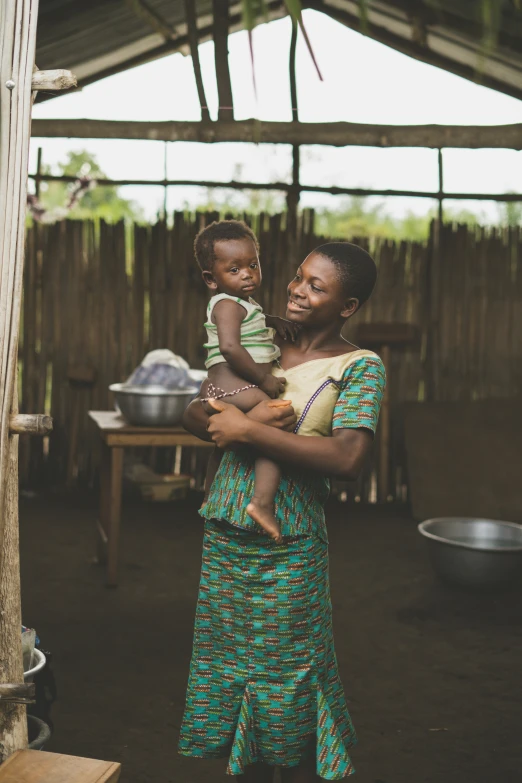 a woman carrying a child while holding soing in her hand