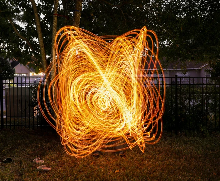 a fire sparkler spinning on the ground near a fence