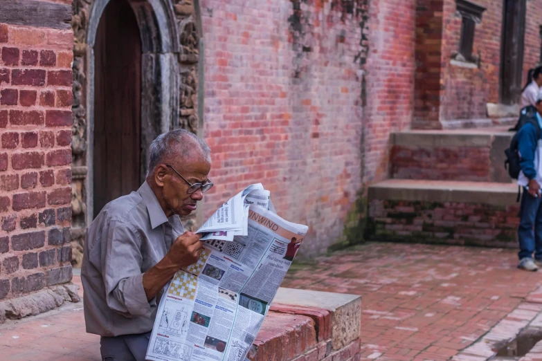 a man is sitting down reading a newspaper