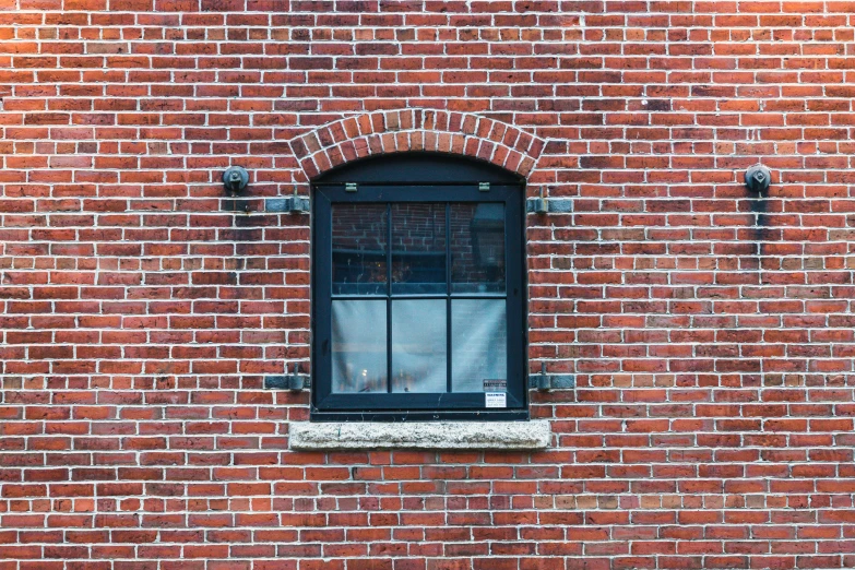 a cat is sitting in the window sill of a red brick building