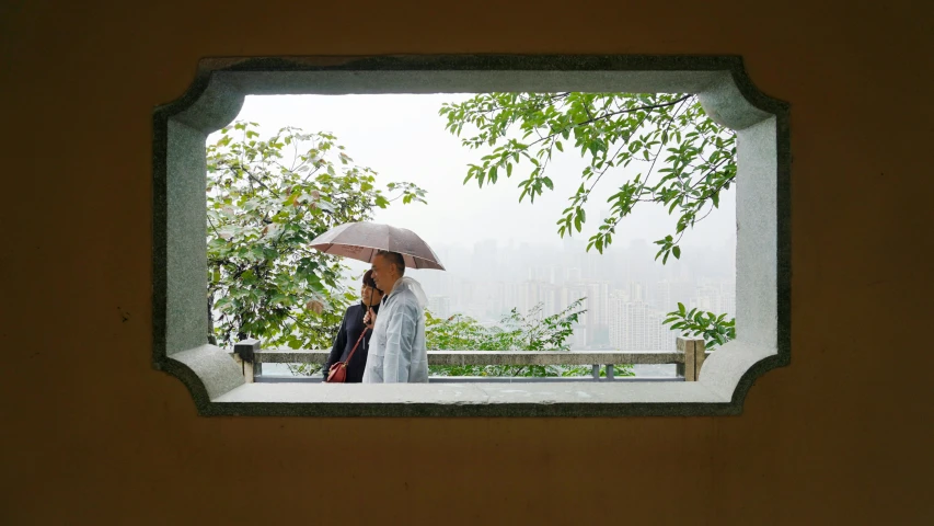 a window with a view shows two women with umbrellas