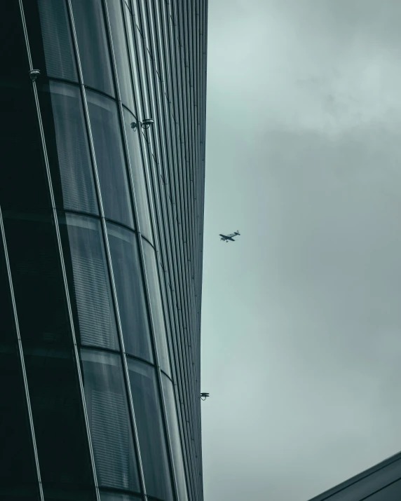 a plane flying near some buildings and a very cloudy sky