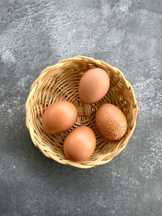 four eggs in a basket on concrete