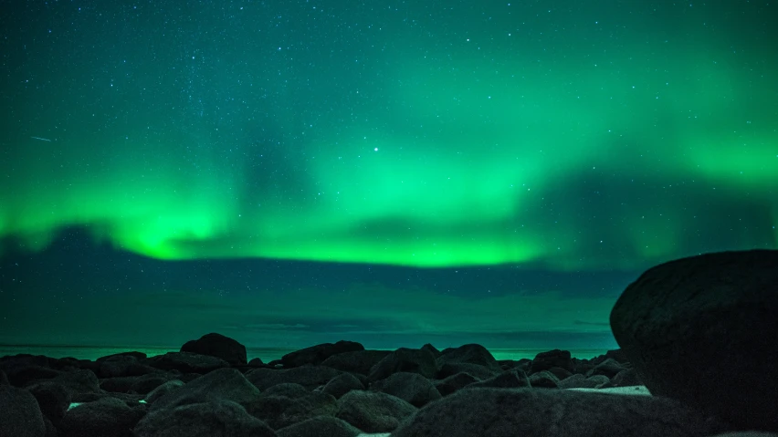 bright green lights in the sky near rocks