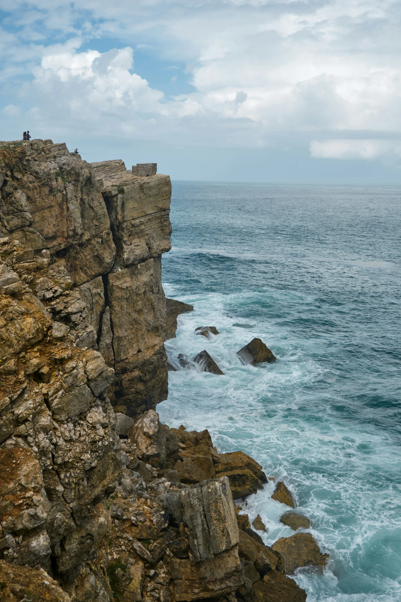 a rocky cliff overlooking the ocean with surfers