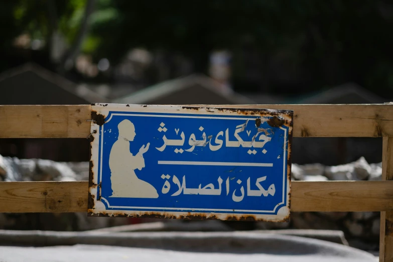 a sign posted above a wooden fence in arabic writing