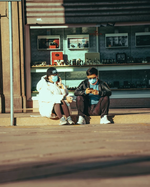 two people sitting on a curb talking to each other