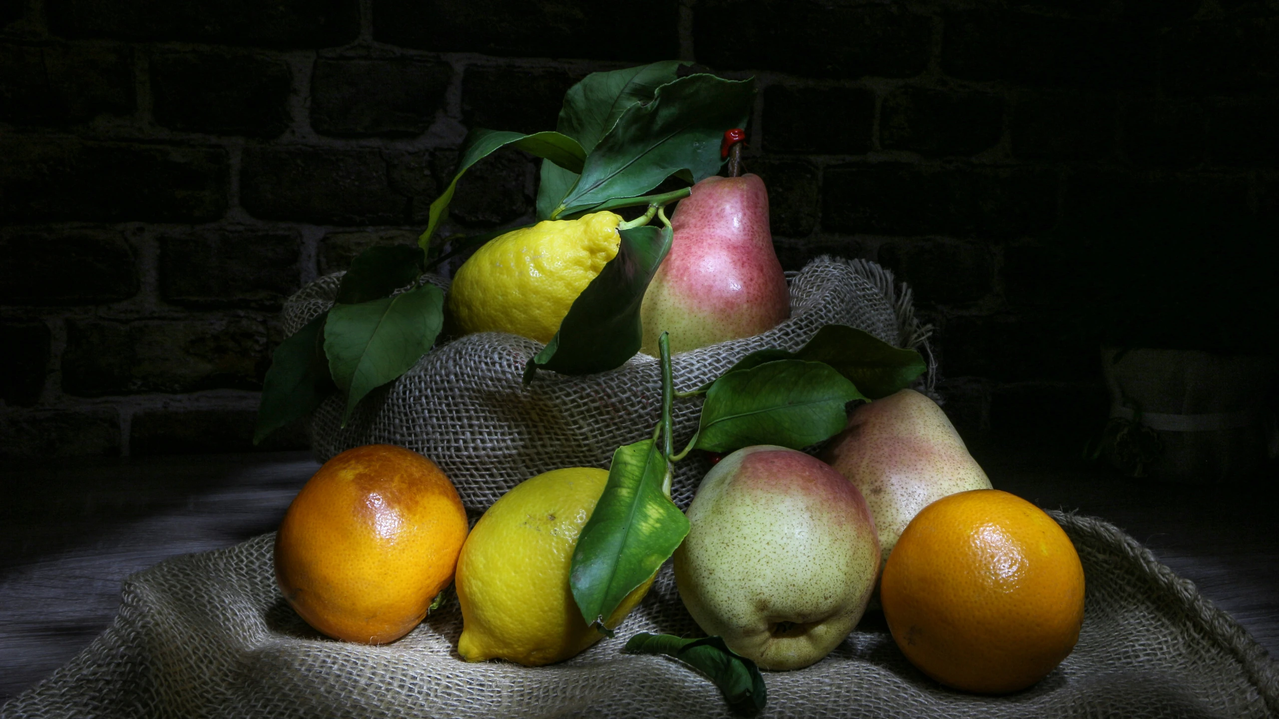 some fruit is in a small basket by a brick wall