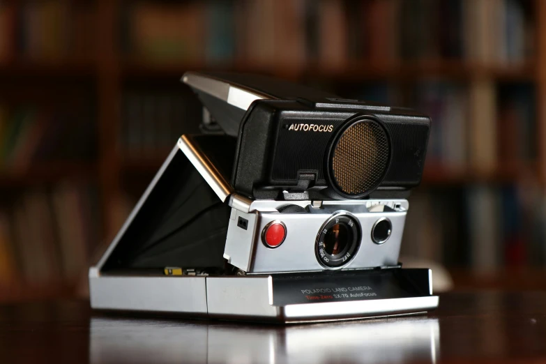 a vintage camera with its lens facing the camera and on the bookcase