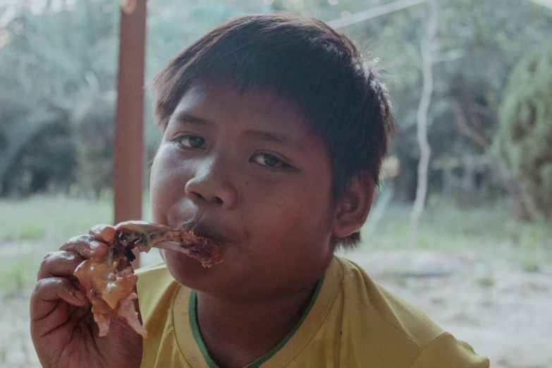 a boy holding food up to his mouth