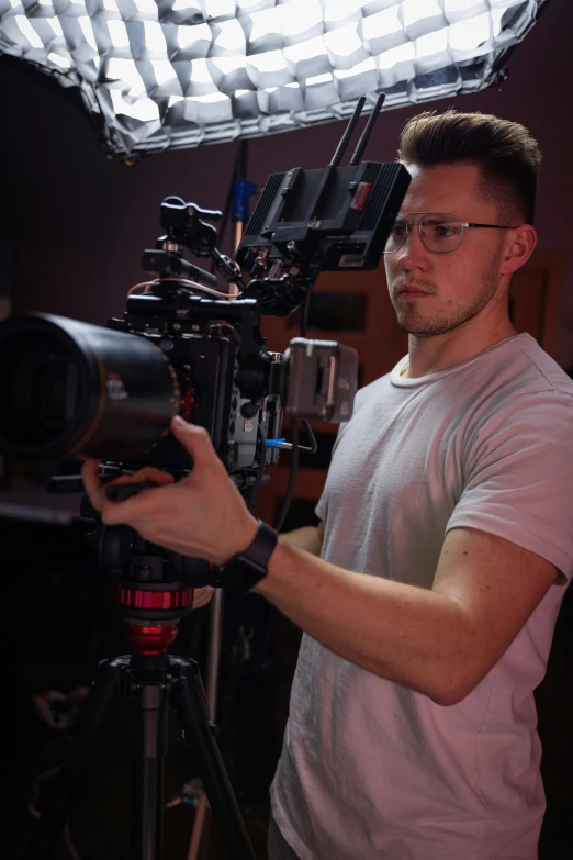 man using video camera and lighting equipment in studio