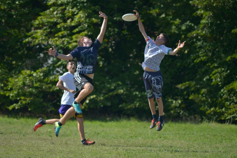 three guys jumping up to catch the frisbee