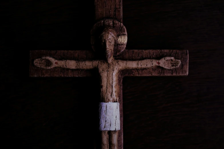 a wooden crucifix with nails and a tag stuck to it