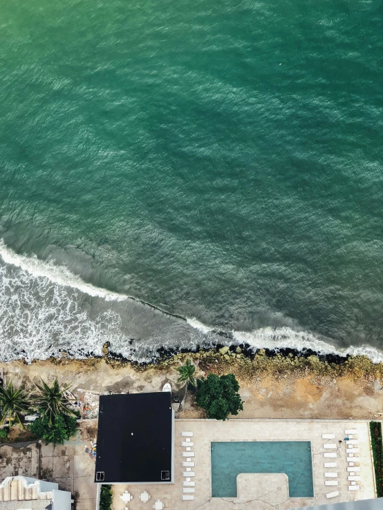 an aerial s of a beach in front of a building with umbrellas on it