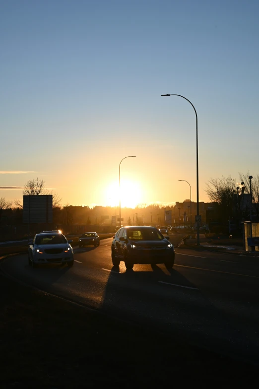 the sun is setting in the distance on the side of a road